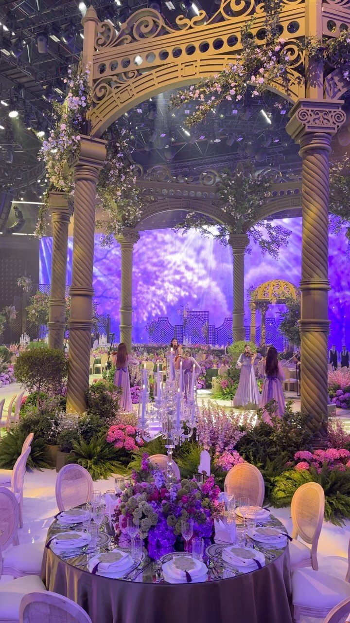 Wedding Decor and Themes: 12 Ideas From Beach to Garden 6 Grand event hall with purple lighting, classical columns, and elaborate floral decorations for a wedding.