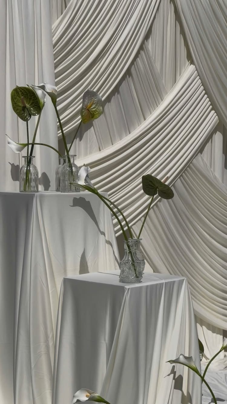 Wedding Decor and Themes: 12 Ideas From Beach to Garden 9 White anthurium flowers in glass vases set against draped white fabric backdrops.