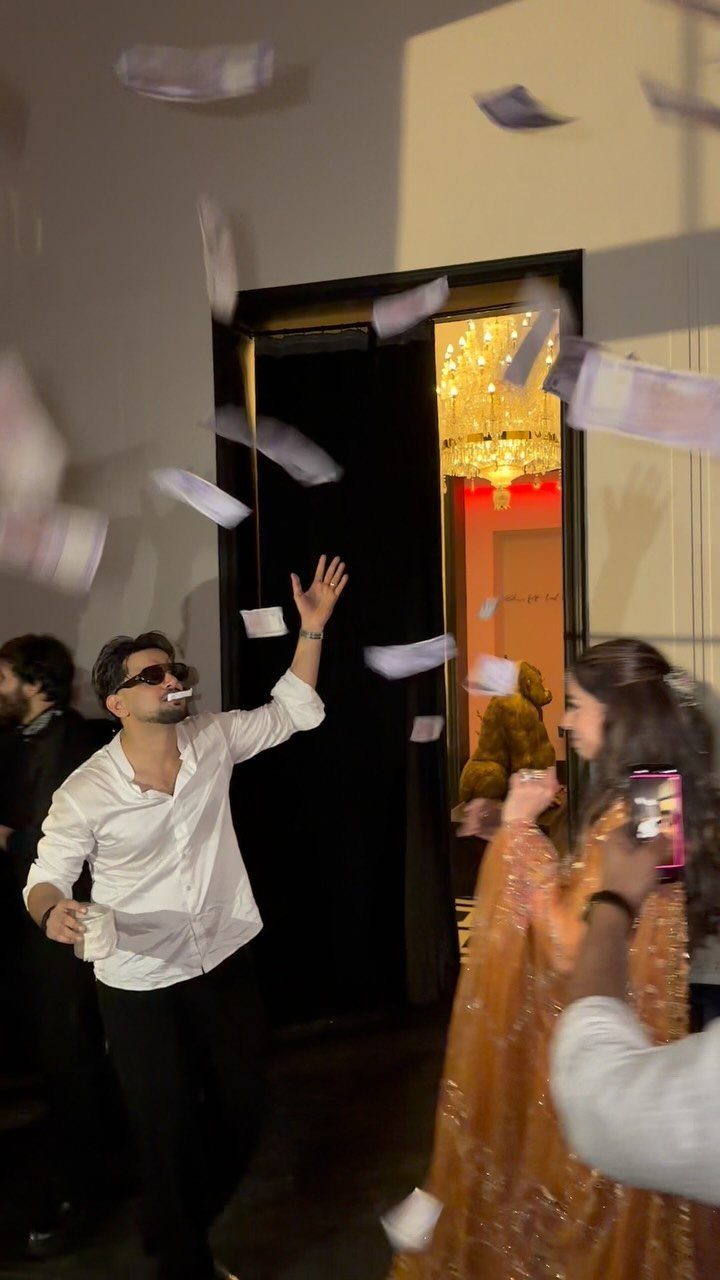 Man in a white shirt throwing paper money into the air during a celebration.