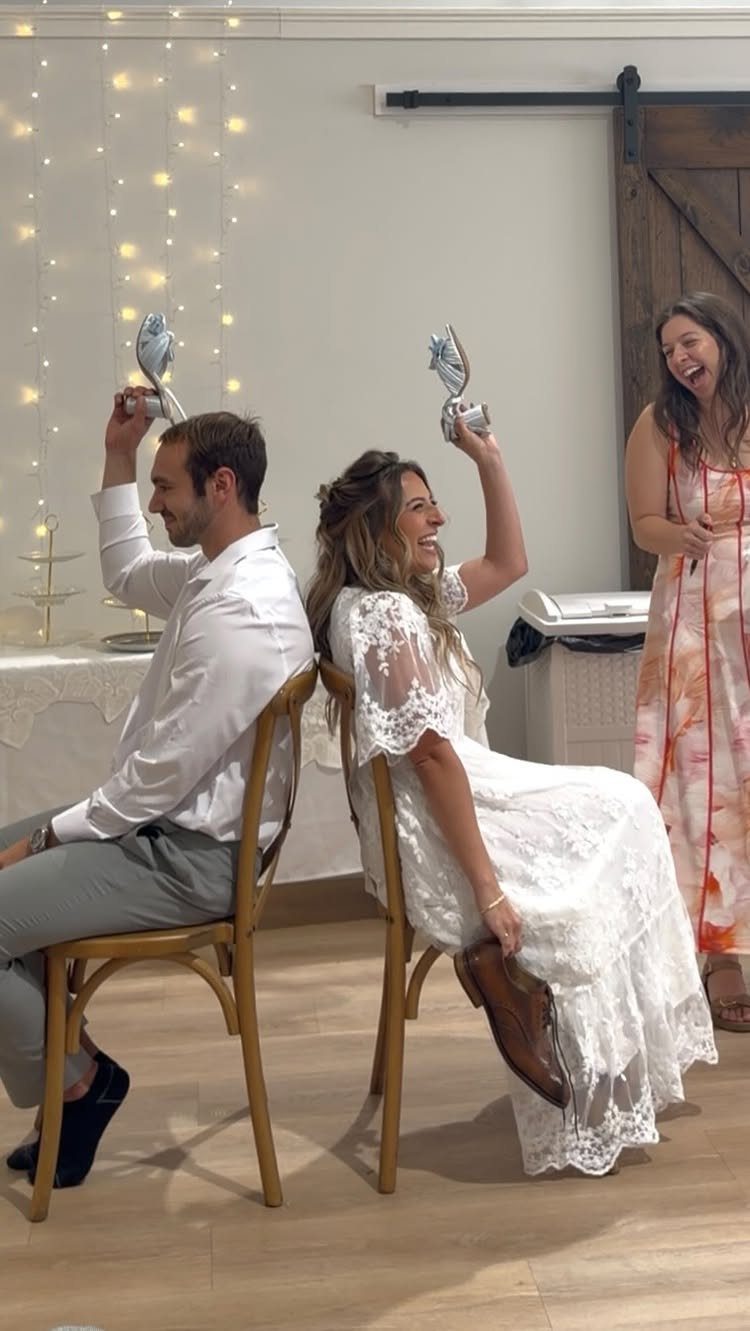 Bride and groom sitting back-to-back playing the shoe game at their wedding reception.