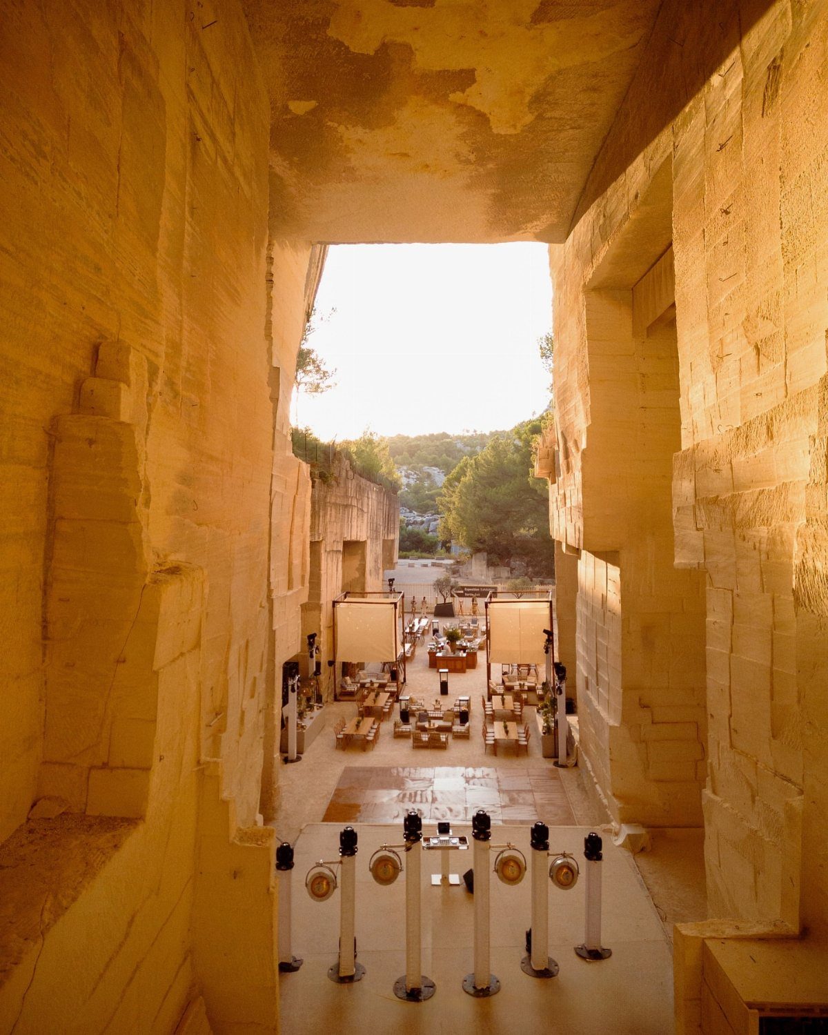 Stone walls framing a view of an outdoor courtyard set with tables and chairs.