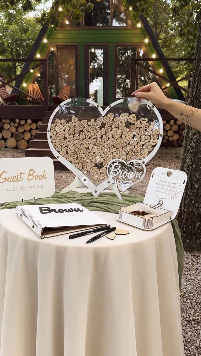 A hand placing a small wooden heart into a large heart-shaped display frame.
