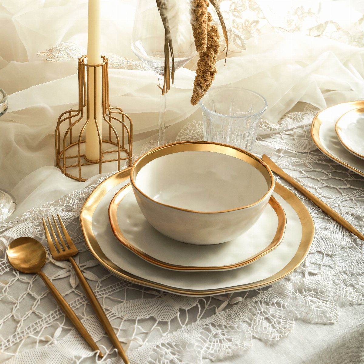 11 Wedding Party Table Decor Ideas for Any Venue Style 2 Gold-rimmed white ceramic plates and gold cutlery arranged on a white lace tablecloth.
