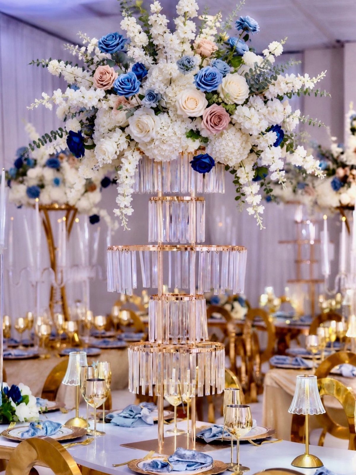 11 Wedding Party Table Decor Ideas for Any Venue Style 9 A tall, tiered crystal wedding centerpiece topped with blue and white roses on a decorated table.