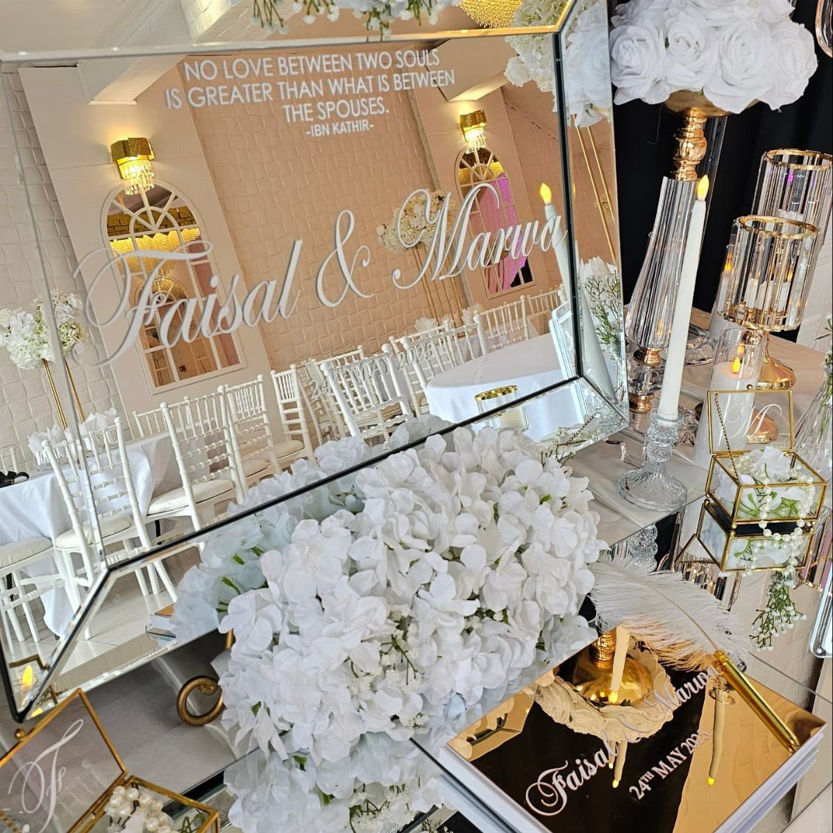11 Wedding Party Table Decor Ideas for Any Venue Style 4 Mirrored wedding sign with white calligraphy surrounded by white flowers and gold decor.