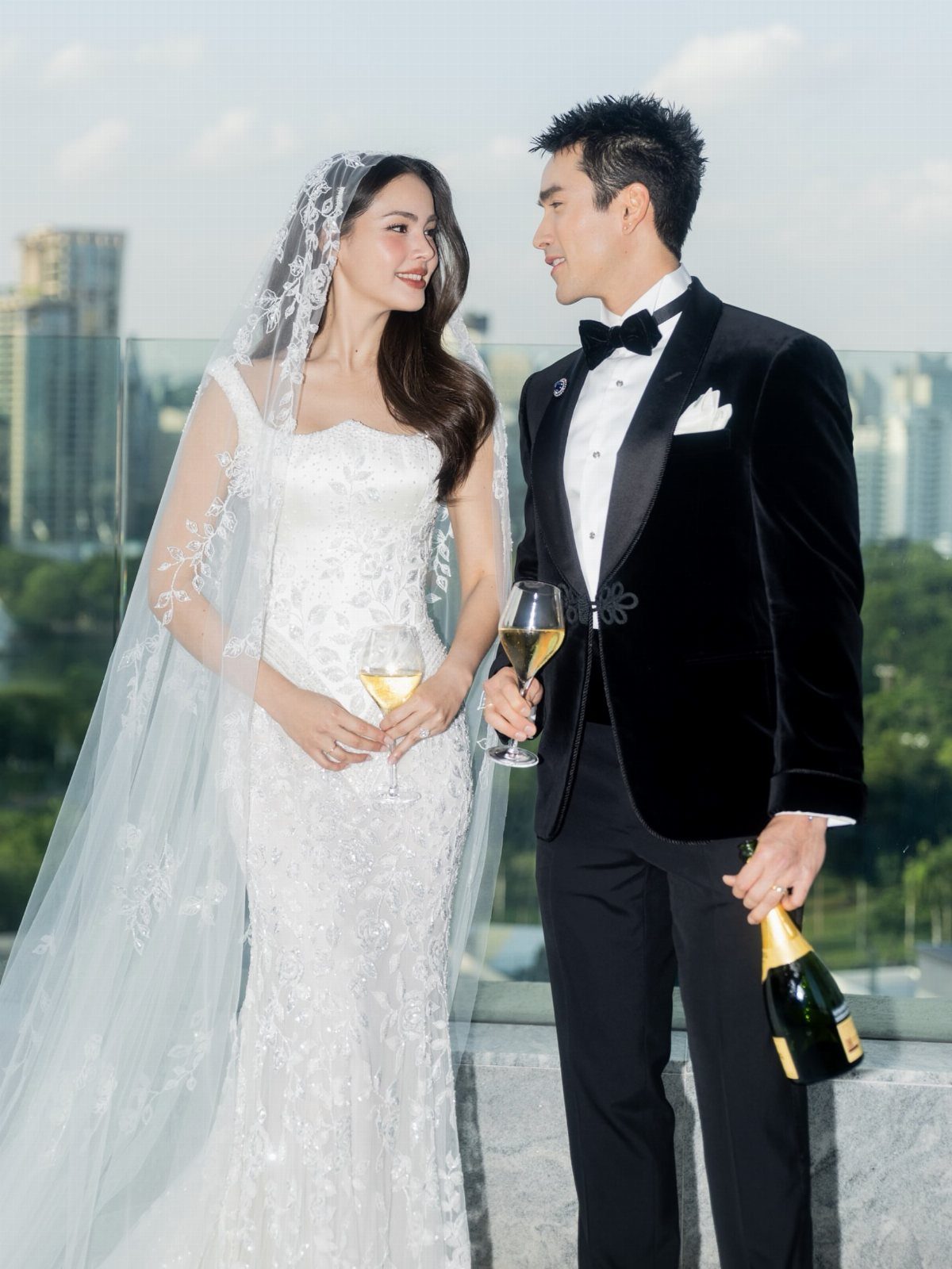 13 Wedding Photo Ideas for Your Shot List 13 Bride and groom in formal wedding attire holding champagne glasses on a city balcony.