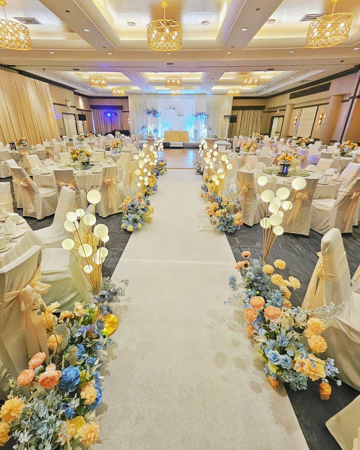 13 Wedding Photo Ideas for Your Shot List 3 A decorated wedding reception hall with a white aisle runner and floral arrangements lining the path.