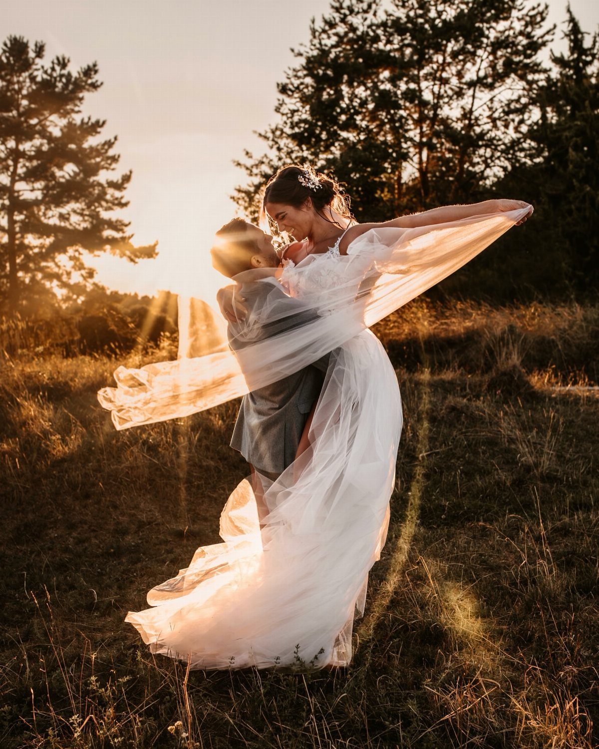 13 Wedding Photo Ideas for Your Shot List 9 A bride and groom embrace in a golden field during a sunset wedding portrait.