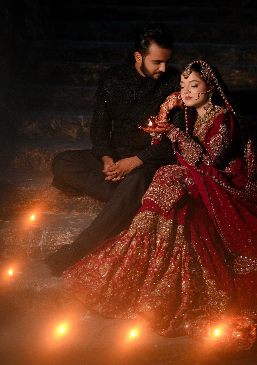13 Wedding Photo Ideas for Your Shot List 4 A bride and groom sit on dark stone steps surrounded by glowing candles at night.