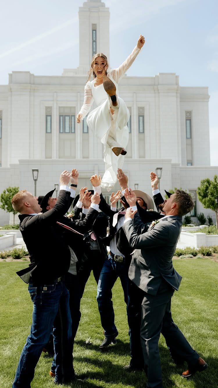 13 Wedding Photo Ideas for Your Shot List 7 A bride being tossed into the air by a group of men in front of a white building.