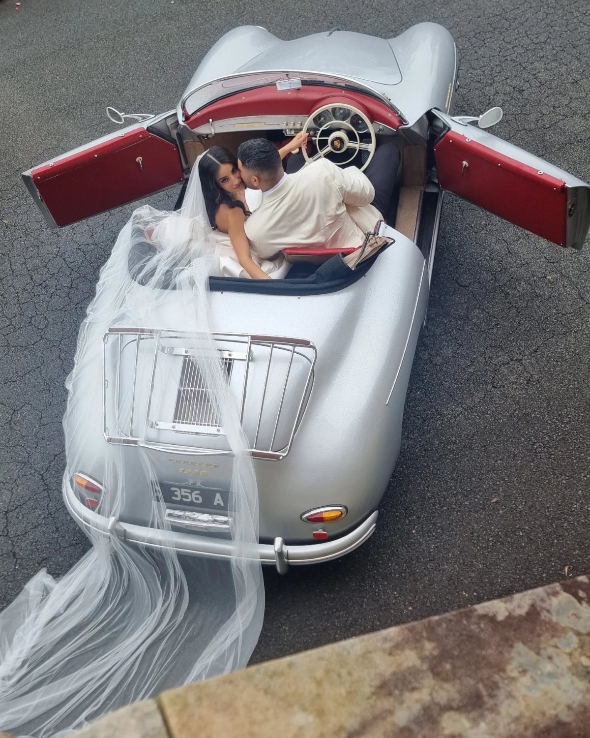 13 Wedding Photo Ideas for Your Shot List 5 A bride and groom lounging inside a silver vintage convertible car from an aerial perspective.