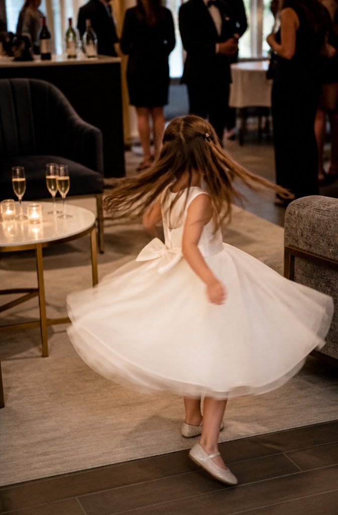 20 Wedding Photography Ideas for 2026 13 Flower girl spinning in her dress at a cocktail hour lounge.