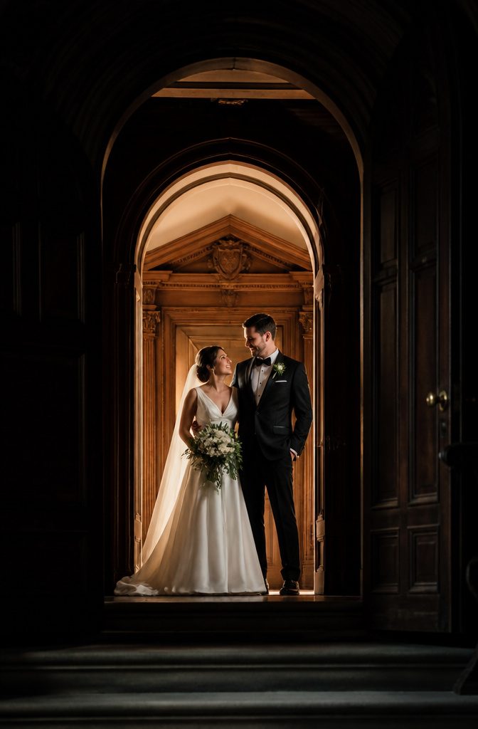 15 Wedding Photo Ideas for Bride and Groom | Poses Guide 2026 4 Bride and groom standing in a doorway with warm light.