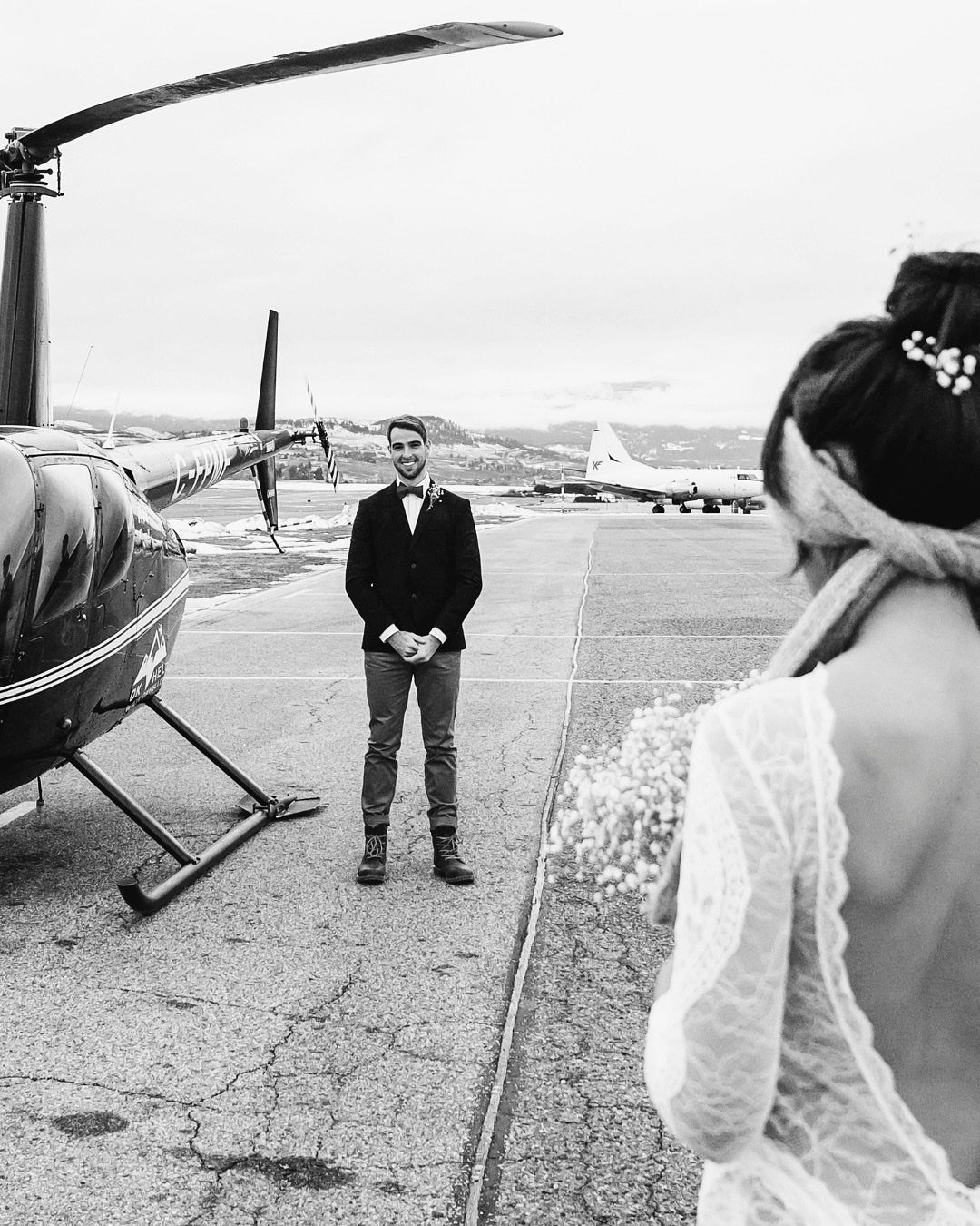9 Wedding Photos Poses for Every Part of Your Day 1 A blindfolded bride approaches her groom standing on an airfield next to a helicopter.