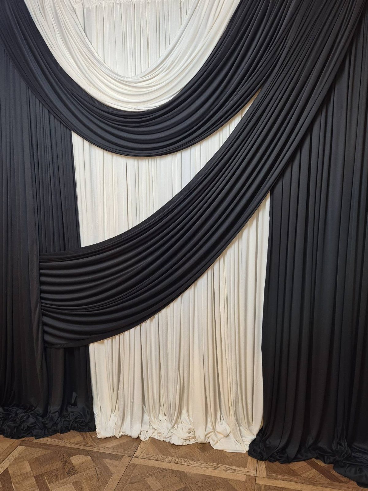 Black fabric swags draped elegantly over a white pleated curtain backdrop.