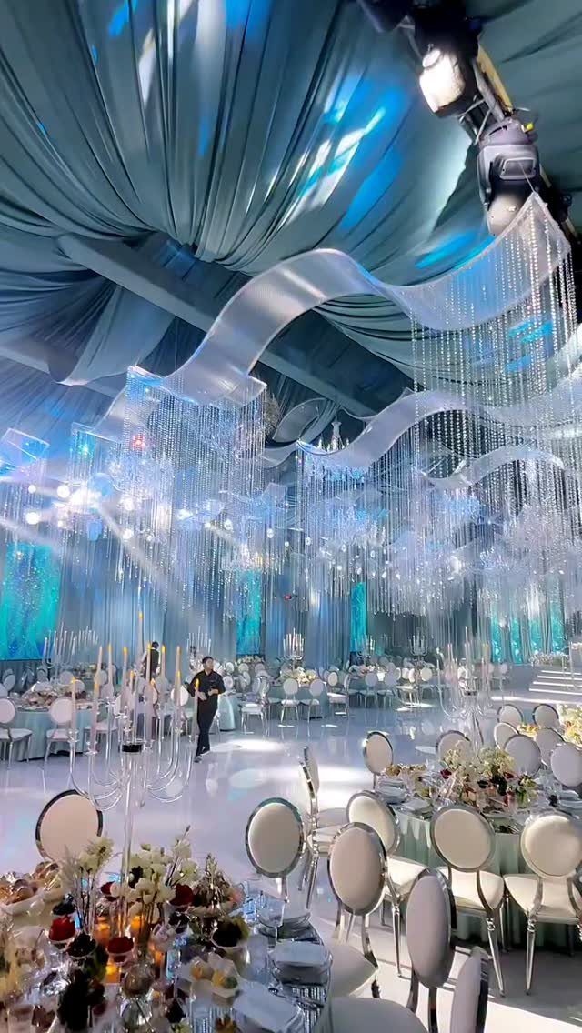 10 Wedding Theme Teal Ideas for Color, Decor and Attire 7 A grand wedding reception hall decorated with teal draped ceilings and hanging crystal chandeliers.