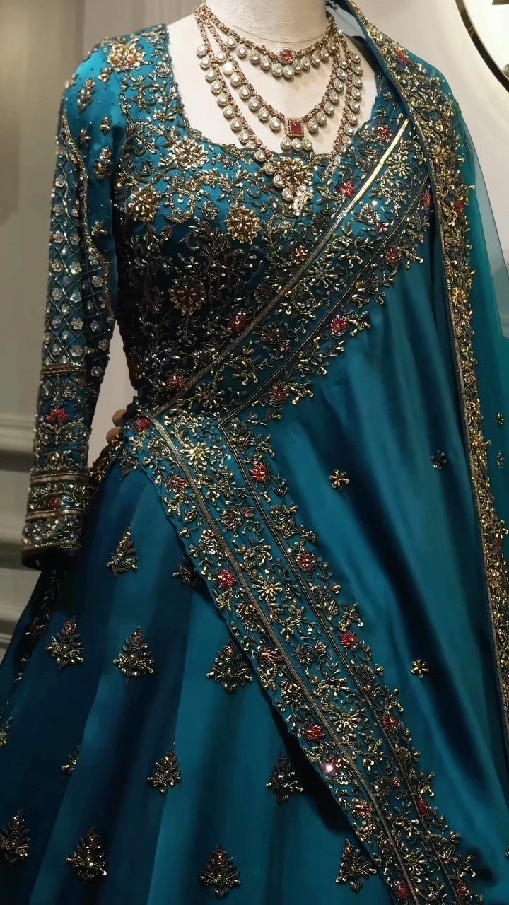 10 Wedding Theme Teal Ideas for Color, Decor and Attire 5 Teal embellished formal gown with gold embroidery and a pearl necklace on a mannequin.