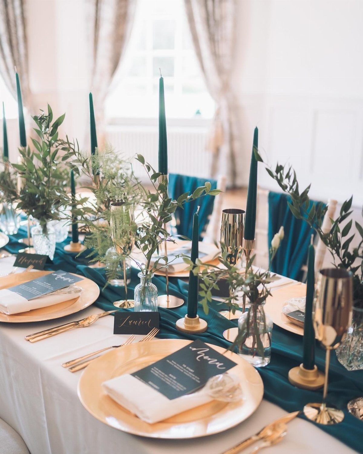 10 Wedding Theme Teal Ideas for Color, Decor and Attire 2 A wedding table decorated with teal runners, gold plates, teal candles, and green leafy centerpieces.