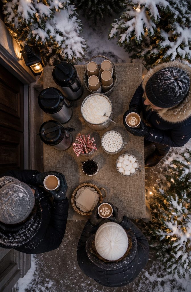 A hot cocoa station with marshmallows and stirrers.
